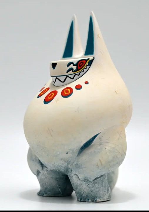 A white bipedal creature with long pointy ears and a mischievous grin. It has red eyes and red circles at the top of its chest almost like a pearl necklace