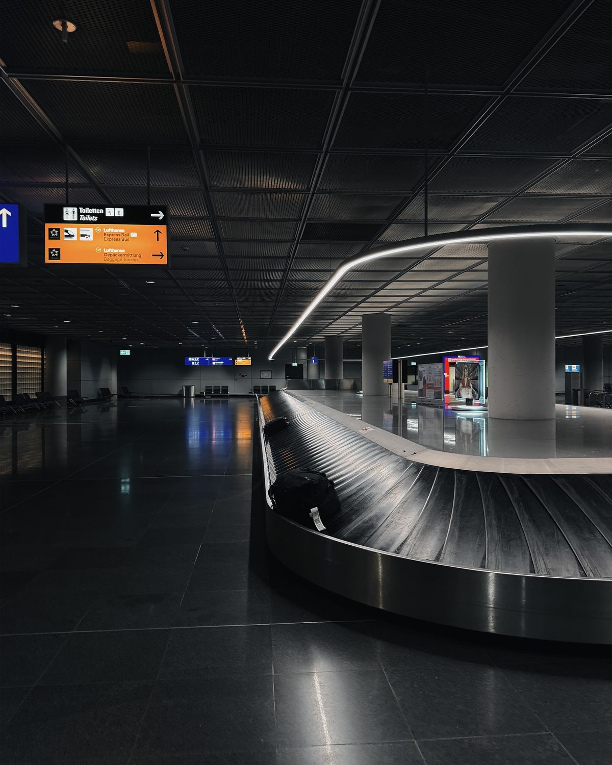 A dimly lit view of Zurich Airport and the luggage carousel
