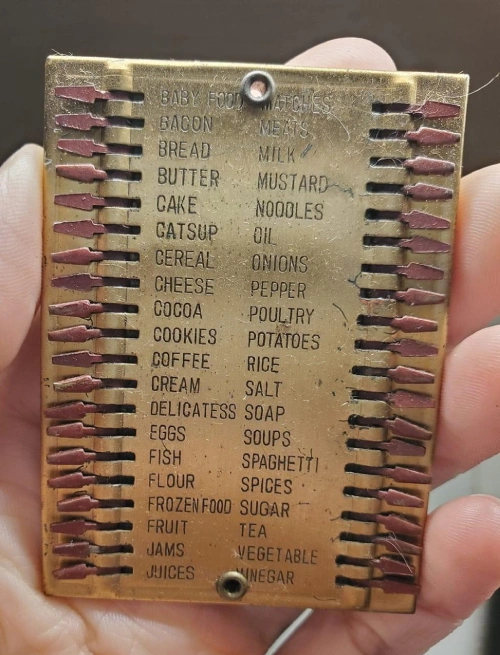 a resuable grocery list made of metal with little arrow shaped appendages to indicate what has been bought