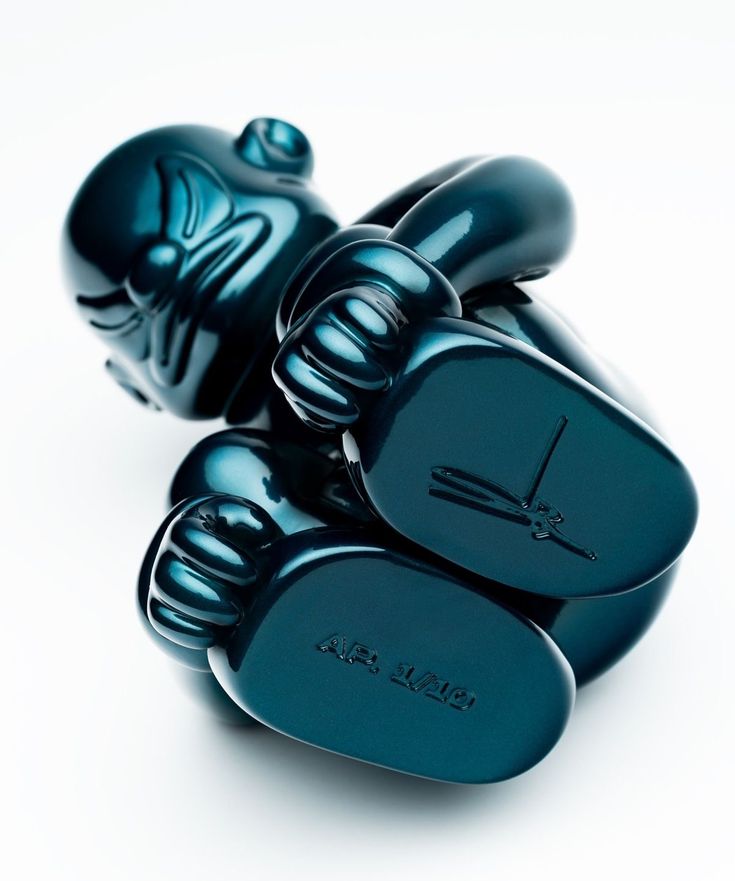a humanoid sculpture curled up in the foetal position, made from dark teal resin and fibreglass